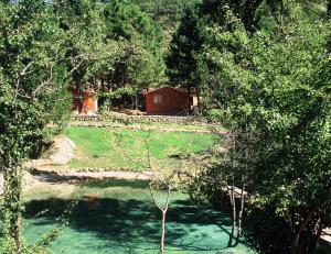 una pequeña cabaña roja en medio de un río en Cabañas La Toma del Agua en Riópar