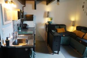 een keuken met een wastafel en een woonkamer met een bank bij La SUITE des AUGUSTINS in Baurech