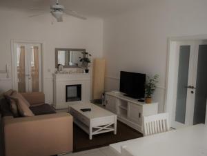 uma sala de estar com um sofá e uma televisão em Orchid Court Apartment. em Għajnsielem