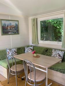 a living room with a table and chairs and a couch at Bungalow la Bouillerie animaux de la ferme in Gonneville-sur-Mer