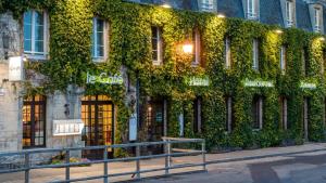 a building covered in green ivy on a street at Hôtel restaurant l'Epicurien in Valognes