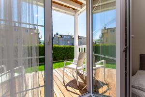 a sliding glass door with a chair on a deck at Willa Verano in Karwia