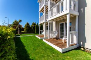 a white house with a deck and lawn at Willa Verano in Karwia