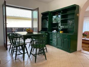 een keuken met groene kasten en een tafel en stoelen bij Szomszéd Ház in Keszthely +14 foto's