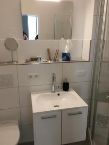 La salle de bains est pourvue d'un lavabo blanc et d'un miroir. dans l'établissement Apartment 6, OG 3, à Schleswig