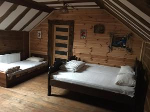 two beds in a room with wooden walls at "Волчья хижина" in Khmelʼnytsʼkyy