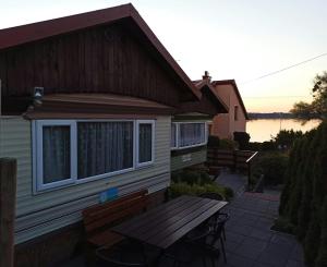 a picnic table in front of a house with a lake at Juno Holiday in Mrągowo +35 photos