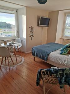 een slaapkamer met een bed en een tafel en een televisie bij Chambres d'Hôtes vue mer entre Plestin les Grèves et locquirec in Plestin-les-Grèves