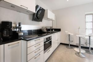 eine Küche mit weißen Schränken und schwarzen Arbeitsplatten in der Unterkunft Maison de village L'A N N E X E proche du port in Saint-Martin-de-Ré