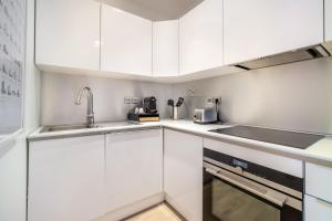 a kitchen with white cabinets and a sink at LA CABANE Lille Centre in Lille