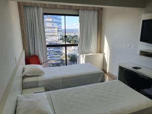 Habitación de hotel con 2 camas y ventana grande. en Brasilia Apart Hotéis, en Brasilia