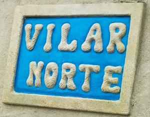 una señal azul con las palabras felices ahora en una pared en Vilar Norte, en Bueu