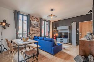 a living room with a blue couch and a table at THE COSY in Arcueil