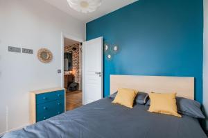 een blauwe slaapkamer met een groot bed met gele kussens bij THE COSY in Arcueil