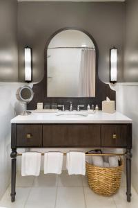 a white sink sitting under a mirror in a bathroom at Hotel Valencia Riverwalk in San Antonio