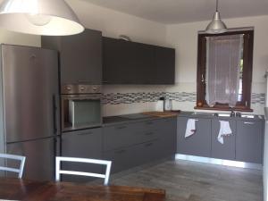 una cocina con nevera de acero inoxidable y armarios grises en Ca' dul Sul, en Miazzina