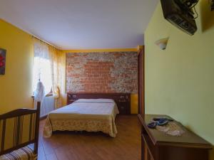 een slaapkamer met een bed en een bakstenen muur bij All'Ombra del Castello in Cigliè
