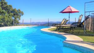 a swimming pool with two chairs and an umbrella at Hotel La Era de Aracena - Adults Only in Aracena