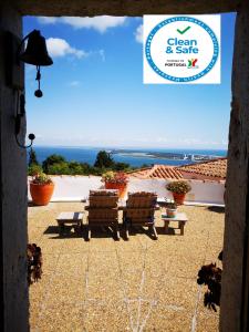 a view of a patio with two benches and the ocean at Moinho do Marco in Setúbal