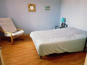 1 dormitorio con 1 cama y 1 silla en Gîte cosy 4 à 9 personnes, en Buffières