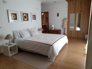 1 dormitorio con 1 cama blanca grande y suelo de madera en First In, en Corroios