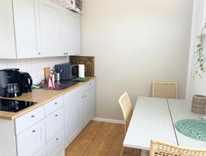 eine Küche mit weißen Schränken und einem Tisch mit einer Mikrowelle in der Unterkunft Apartment Bella in Chemnitz
