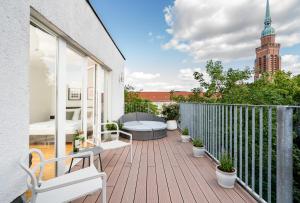 balcón con terraza de madera y sofá en BENSIMON apartments Prenzlauer Berg, en Berlín