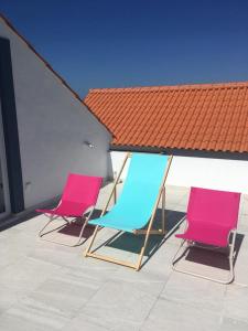 3 chaises assises sur un patio avec un toit dans l'établissement Villa Ricardo, à Alcobaça