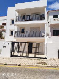 een wit appartementencomplex met een zwart hek bij Paradise in Olhos D'água Beach in Albufeira