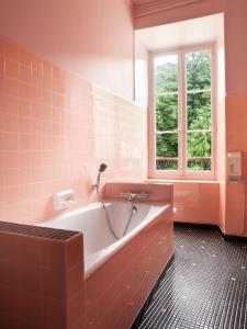 ein Bad mit einer Badewanne und einem Fenster in der Unterkunft Grand Hôtel du Parc in Florac Trois Riviere