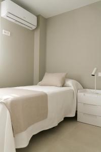 a white bedroom with a bed and a night stand at Sosiego Home in Puerto de Mazarrón