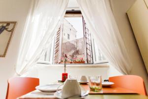 a table with orange chairs and a window at Maison Colosseo (Via dei Querceti 24) in Rome