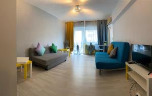 uma sala de estar com duas cadeiras azuis e uma televisão em green Apartment 96 em Bucareste