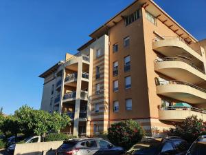a tall building with cars parked in front of it at Appartement 2 pièces Cosy au calme climatisé 3 étoiles in Fréjus