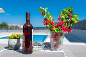 Una botella de vino sentada junto a un jarrón de flores. en Aegean Horizon apartments en Gennadi