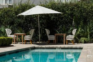 a table and chairs and an umbrella next to a pool at Hotel Ella in Austin