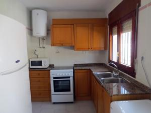 cocina con armarios de madera y horno de fogón blanco en Peñíscola: apartamento con piscina, en Peñíscola