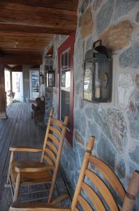 two wooden chairs on a porch with a stone wall at The Country Inn of Lancaster in Lancaster