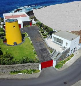 dom z żółtą wieżą nad oceanem w obiekcie Wellshouses w mieście Capelas