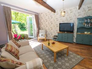 a living room with a couch and a tv at Bilberry Nook Cottage in Westgate