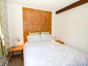 a bedroom with a bed and a wooden headboard at Bilberry Nook Cottage in Westgate