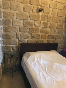 Ce lit se trouve dans une chambre dotée d'un mur en briques. dans l'établissement Kasr-i Abbas Hotel, à Mardin