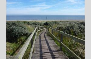 a wooden boardwalk leading to a beach with the ocean at Luxury Holiday Home in Anderby Creek in Anderby