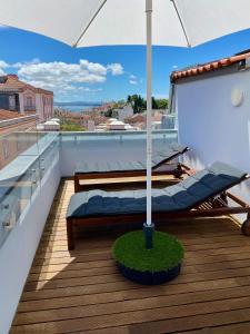 a balcony with a bed and an umbrella on a roof at Unique apartment by MyPlaceForYou, in the center of Lisbon with views over the city and the Tagus river in Lisbon