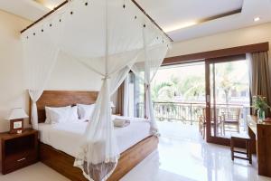 a bedroom with a canopy bed and a balcony at Outpost Ubud Nyuh Kuning in Ubud