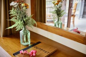 a wooden table with two vases with flowers on it at Outpost Ubud Nyuh Kuning in Ubud