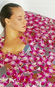 a woman laying in a bathtub with purple and white flowers at Hotel JD Utsunomiya (Adult Only) in Utsunomiya