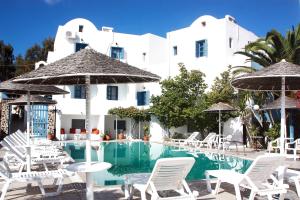 a hotel with a swimming pool and white chairs and umbrellas at Hotel Kalma in Mesaria