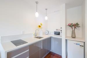 a white kitchen with a sink and a microwave at Auckland Newmarket Motel in Auckland