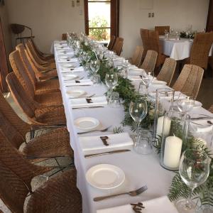 a long table with white plates and wine glasses at Beach Huts Middleton in Middleton